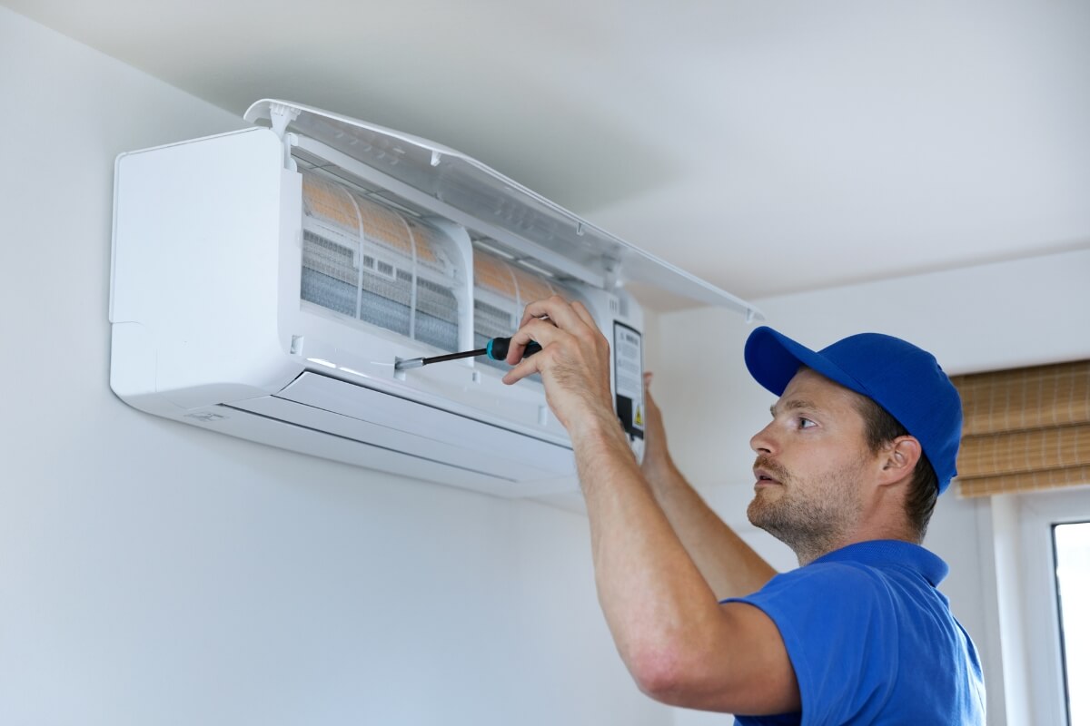 technician-installing-ac Service Technician Installing Air Conditioner on wall