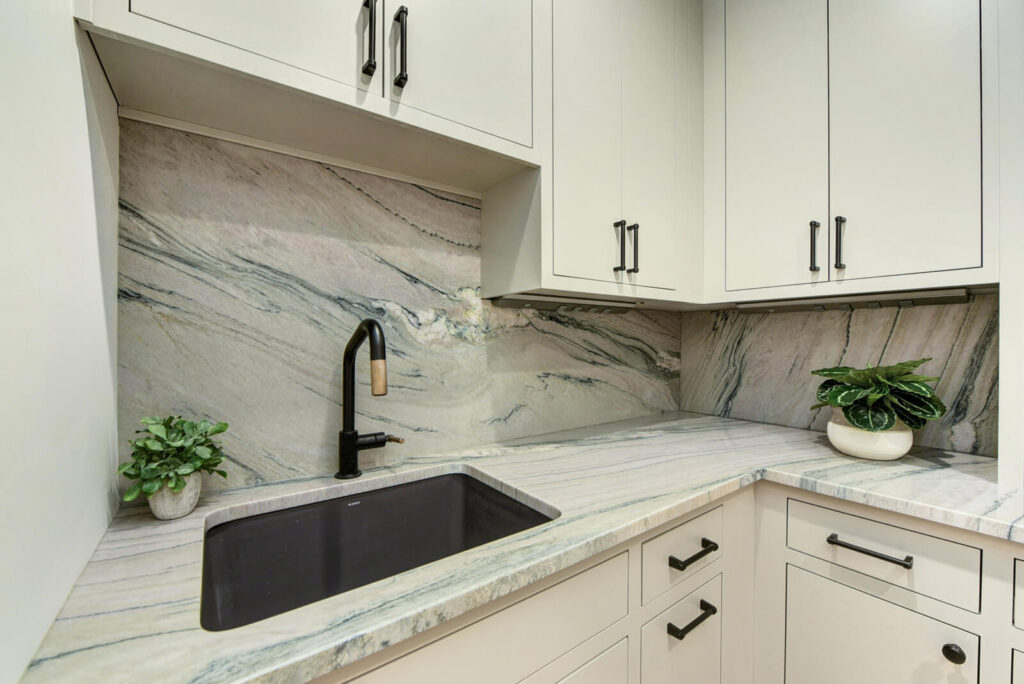 A modern kitchen featuring elegant white cabinets and luxurious marble countertops, creating a bright and sophisticated atmosphere.
