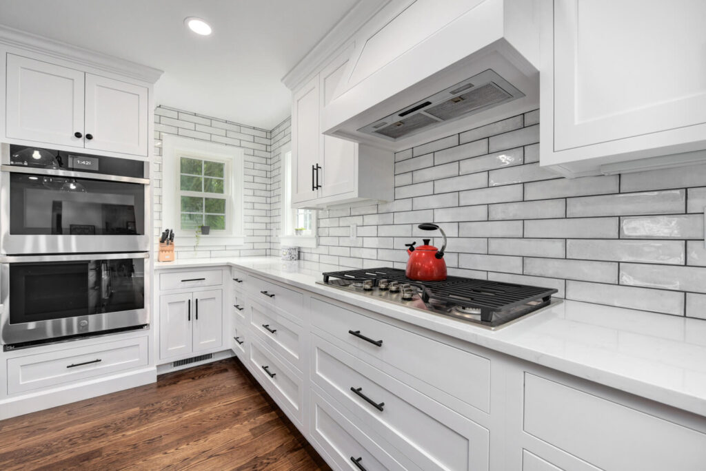 A modern kitchen featuring white cabinets and a sleek stove top, showcasing a clean and bright cooking space.