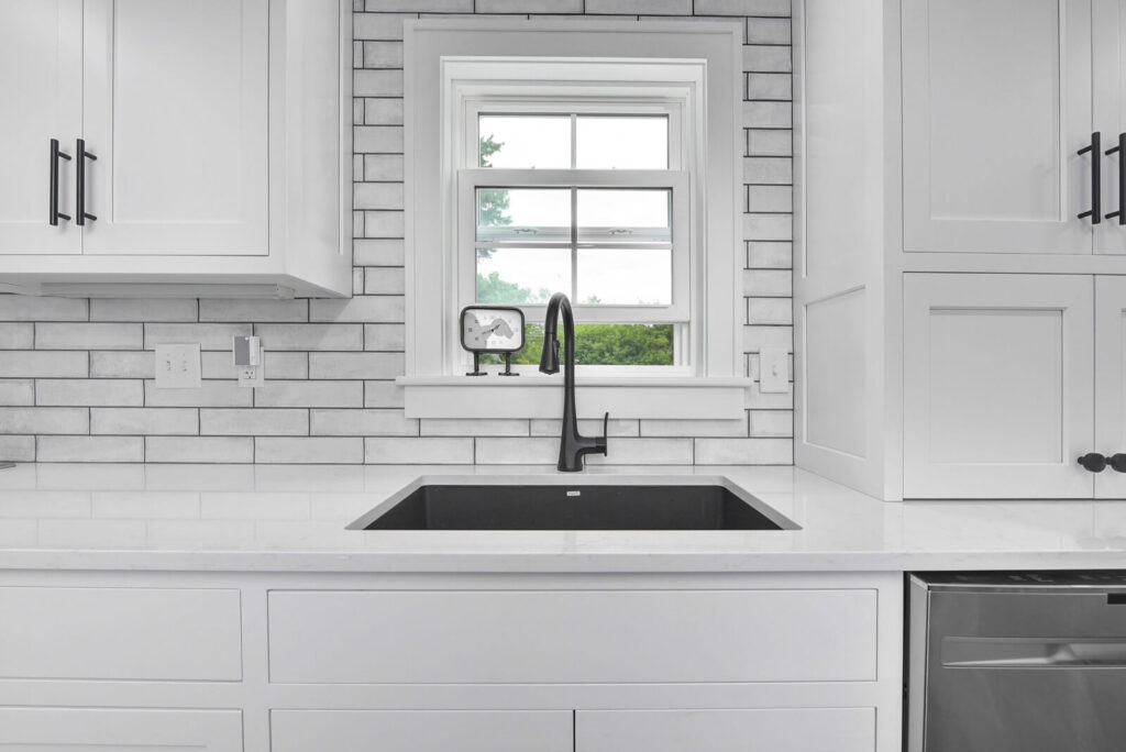 A bright kitchen showcasing elegant white cabinetry alongside sophisticated black appliances for a chic and modern look.