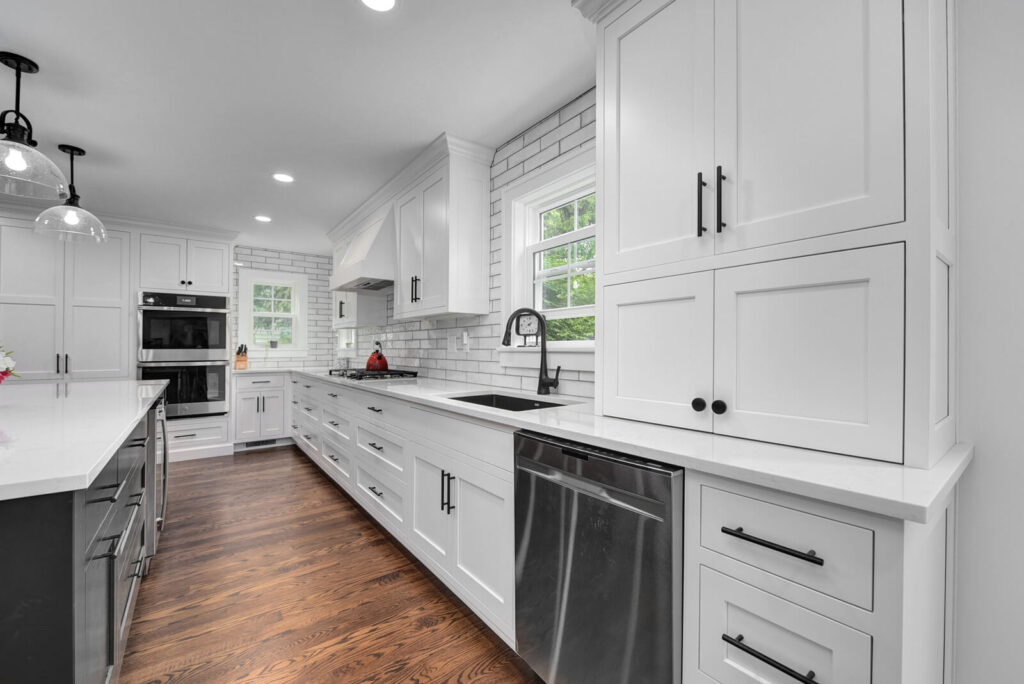 A stylish kitchen showcasing white cabinetry paired with elegant wood flooring, enhancing the overall aesthetic.