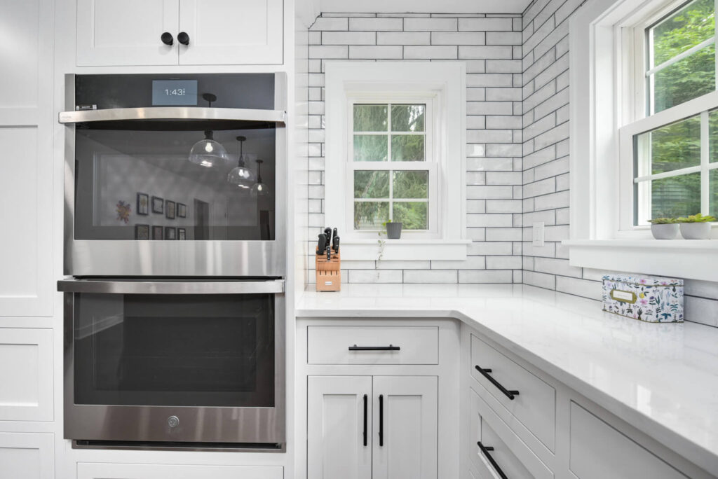 A modern kitchen featuring white cabinets and a sleek stainless steel oven, creating a bright and inviting atmosphere.