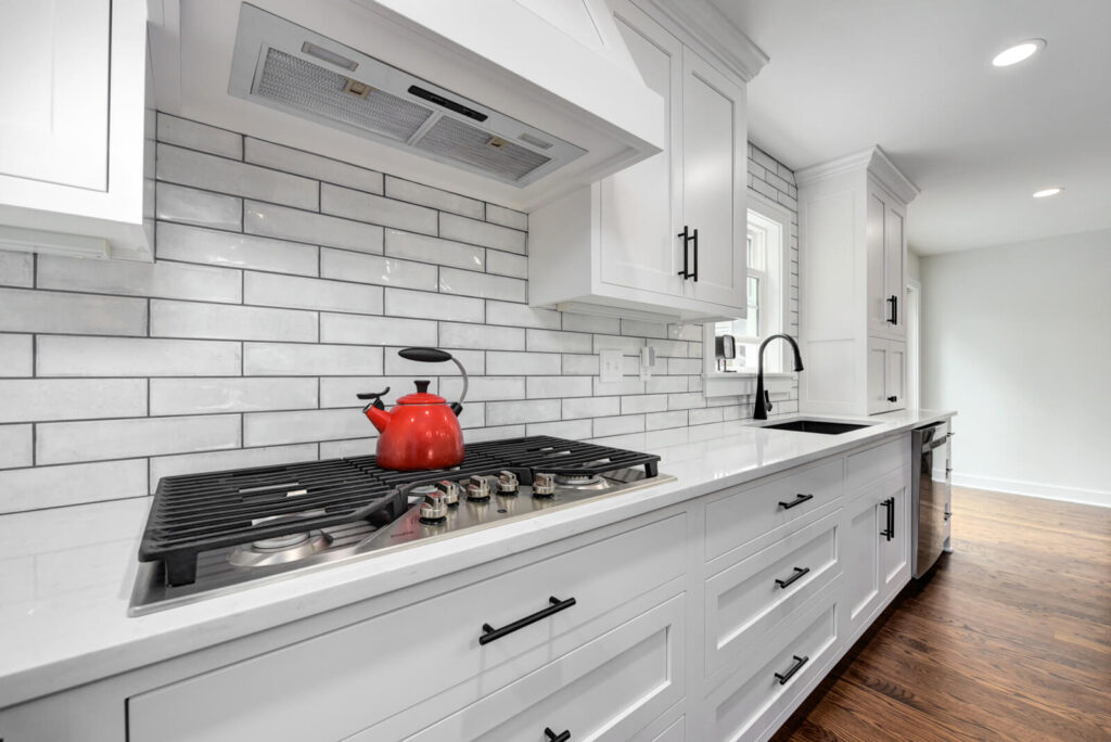 A modern kitchen featuring white cabinets and a sleek stove top, showcasing a clean and bright cooking space.