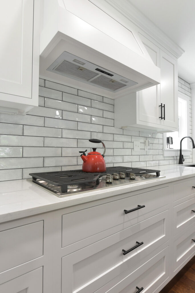 A modern kitchen featuring white cabinets and a sleek stove top, showcasing a clean and bright cooking space.
